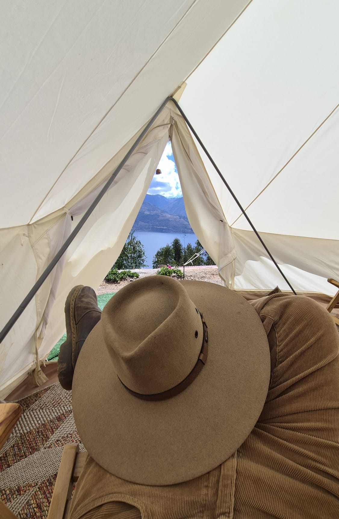 Interior de bell tent con sombrero y vista a la laguna