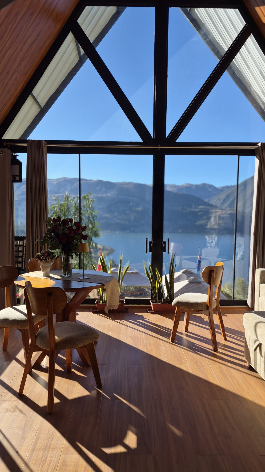 Sala de Casa Alpina con ventanales hacia la laguna Pacucha
