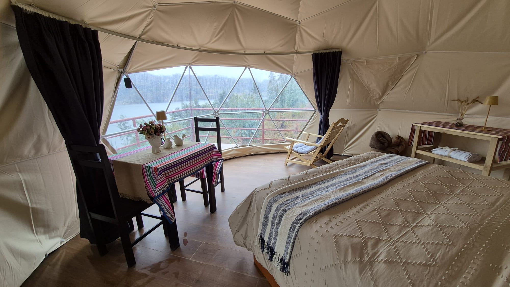 Interior amplio de Los Domos con cama y vista hacia la laguna