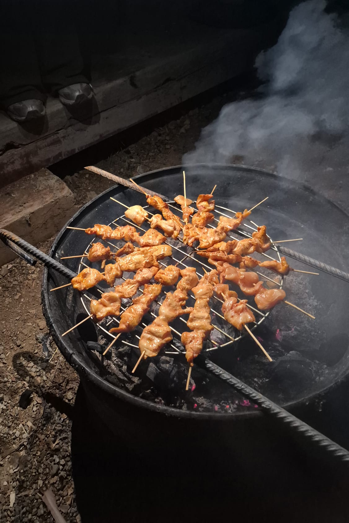 Brochetas cocinándose en la parrilla de noche