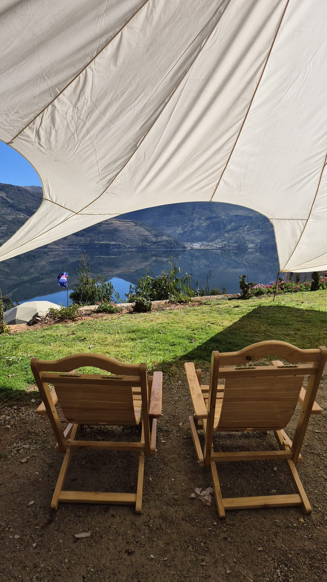 Sillas bajo un toldo con vista a la laguna