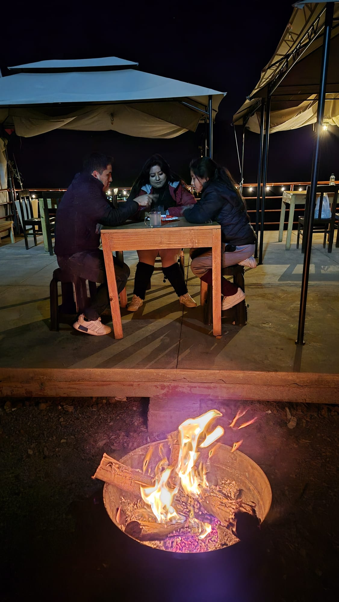 Mesa de noche en terraza con fogata encendida al frente