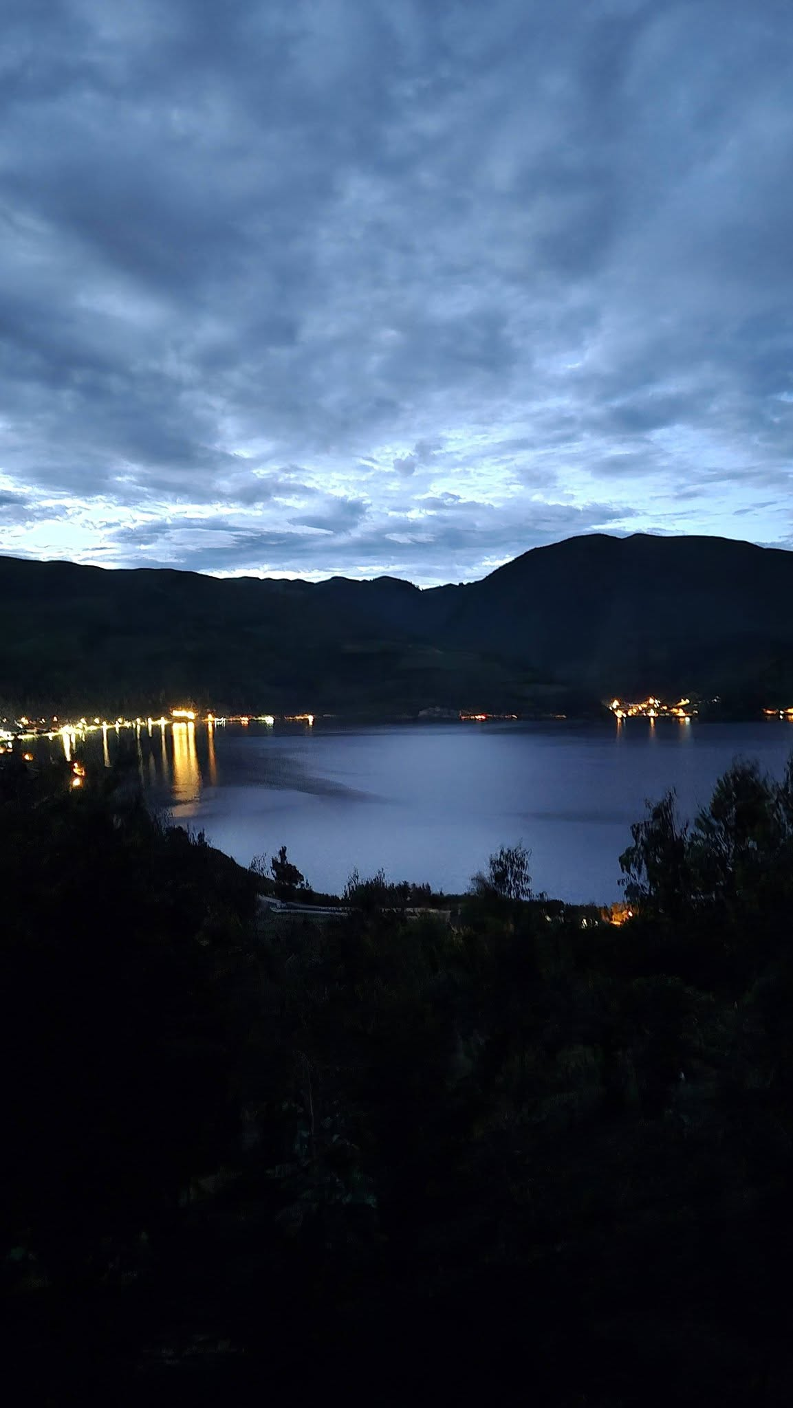 Atardecer sobre la laguna de Pacucha con luces reflejadas